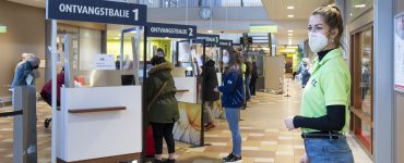 Stewards wijzen iedereen bij de nieuwe ontvangstbalies van het ETZ op de beschermingsmaatregelen en ontvangen de patiënten en bezoekers.