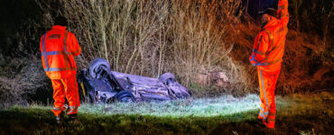 Auto ondersteboven in de sloot met ambulancepersoneel eromheen